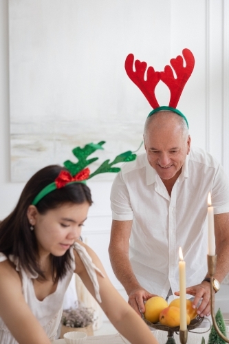 Granddad with granddaughter setting up table at Christmas - Australian Stock Image