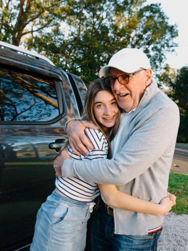 Grandfather embracing granddaughter outside the house. - Australian Stock Image