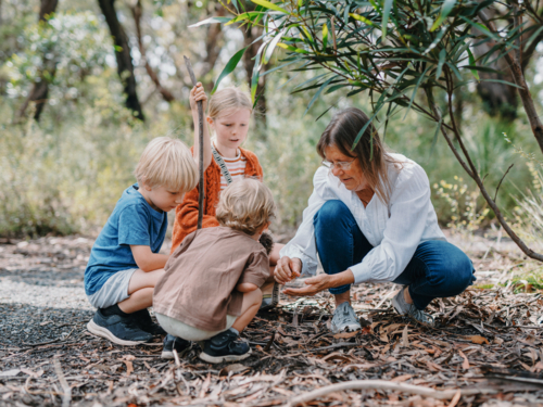 Grandmother enjoying Australian Bushland with her Grandchildren picking up a cicada bug - Australian Stock Image