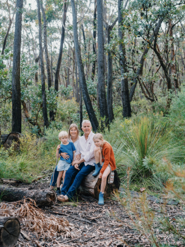 Grandparents enjoying Australian Bushland with their Grandchildren sitting on log - Australian Stock Image