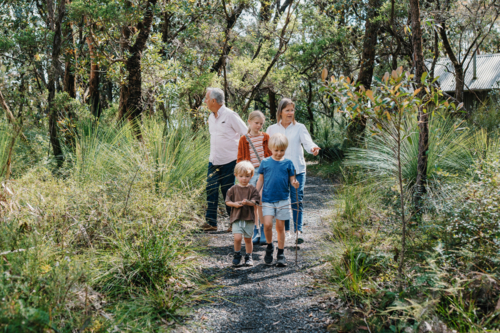 Grandparents enjoying Australian Bushland with their Grandchildren walking down trail - Australian Stock Image