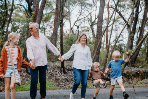 Grandparents enjoying Australian Bushland with their Grandchildren walking while holding hands - Australian Stock Image