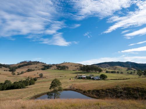 Grazing country with a farm dam, house and hills - Australian Stock Image