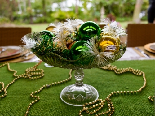 Green and Gold Christmas table decorations in blurred outdoor area - Australian Stock Image