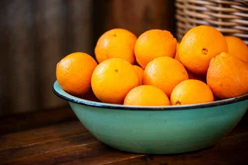 green enamel bowl of oranges - Australian Stock Image