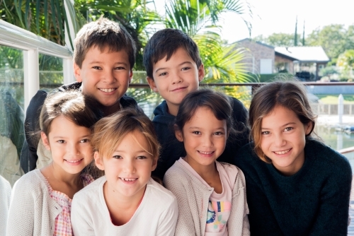 Group of children close together smiling at the camera. - Australian Stock Image