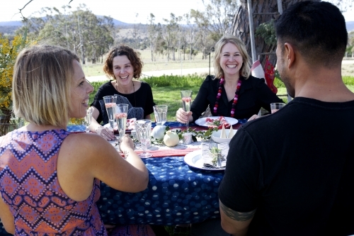 Group of people sitting at a table outside on Christmas day - Australian Stock Image