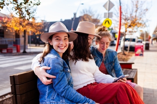 Group of three teenaged friends sitting together in urban area of town - Australian Stock Image