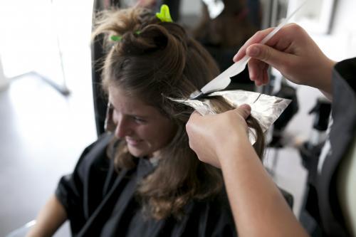 Thoughtful woman sitting with foil on hair at salon stock photo