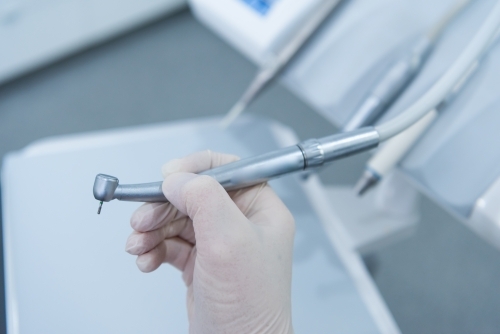 Hand holding dental handpiece - Australian Stock Image