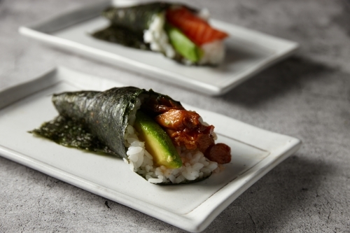 Hand rolled sushi served in a square white plate - Australian Stock Image