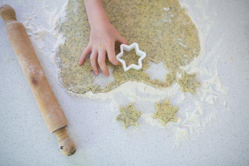 Hands cutting out biscuit dough - Australian Stock Image