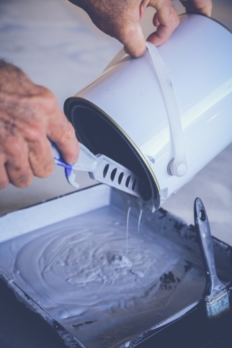 Hands pouring paint into tray - Australian Stock Image