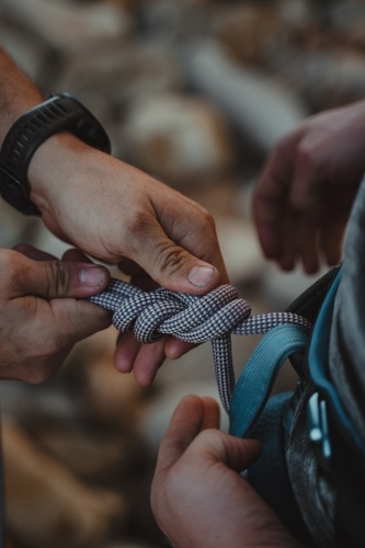Hands tying a rethreaded figure eight in rope onto a climbing harness - Australian Stock Image