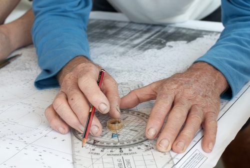 Hands with pencil marking sailing navigation points - Australian Stock Image