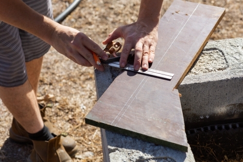 Handyman measuring chipboard for diy project - Australian Stock Image