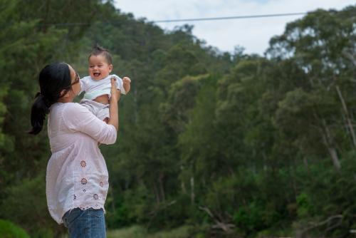 Happy Asian mum with her mixed race baby boy outside - Australian Stock Image