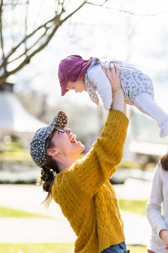 Happy aunty in her twenties playing with baby niece outside - Australian Stock Image
