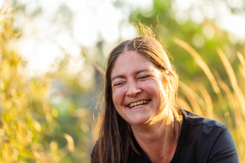Happy Australian woman laughing in golden sunset light outdoors - Australian Stock Image