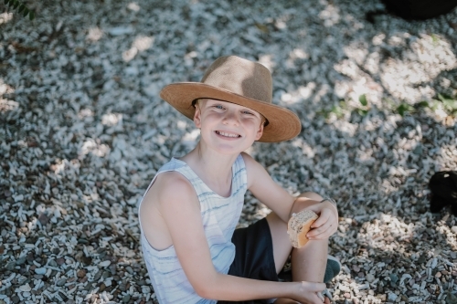 Happy boy having a snack on beach covered in coral in the Whitsundays - Australian Stock Image
