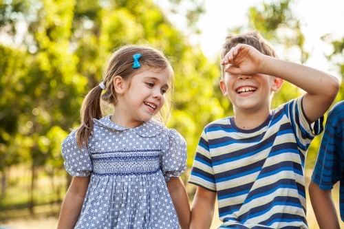 Happy brother and sister laughing together outside - Australian Stock Image