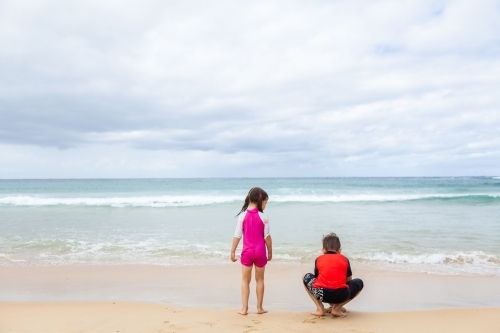 Happy brother and sister playing together on the beach - Australian Stock Image