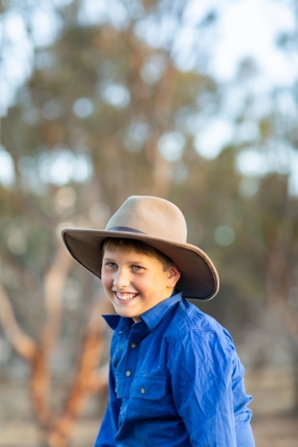 Happy country kid wearing felt hat in the bush - Australian Stock Image