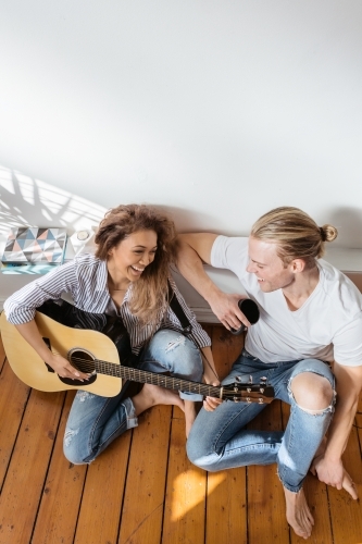 Happy couple playing guitar with clear space above - Australian Stock Image