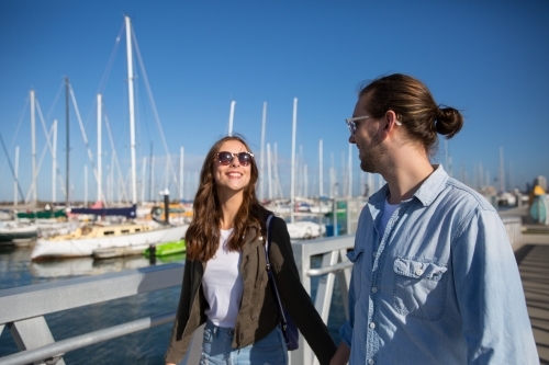 Happy couple walking together at the Marina on a sunny day - Australian Stock Image