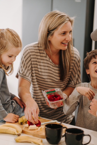 Happy family helping each other prepare food in the kitchen. - Australian Stock Image