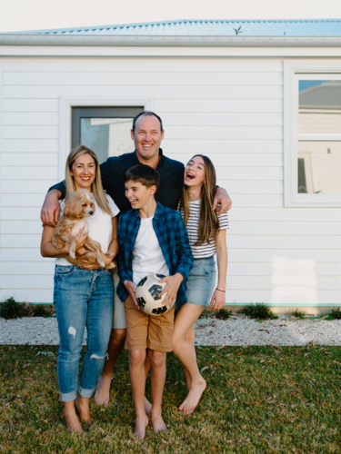 Happy family standing barefoot in their yard. - Australian Stock Image