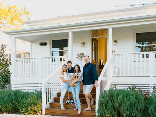 Happy family standing on wooden steps of their porch of Australian home - Australian Stock Image