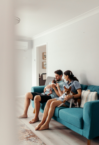 Happy family with newborn baby sitting on the lounge - Australian Stock Image