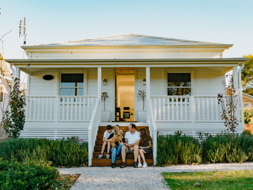 Happy family with their dog sitting on the steps of their home. - Australian Stock Image