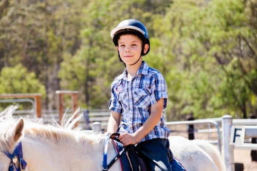 Happy kid on white pony - riding lessons - Australian Stock Image