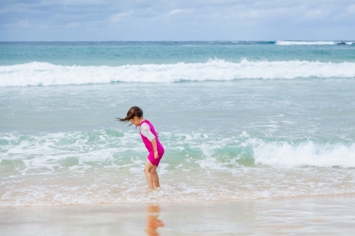 Happy kid running and splashing in seaside waves at the beach - Australian Stock Image