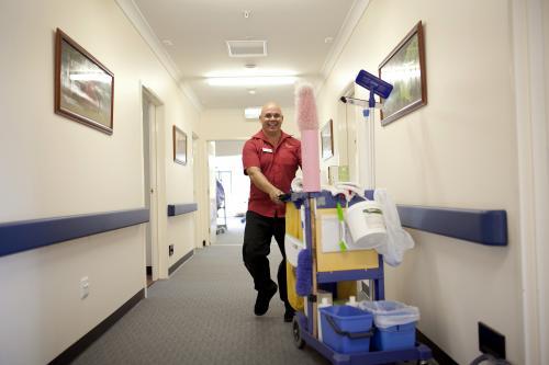 Happy male nursing home cleaner doing rounds