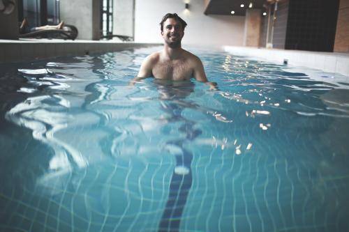 Happy male swimmer enjoying contemporary indoor lap pool - Australian Stock Image