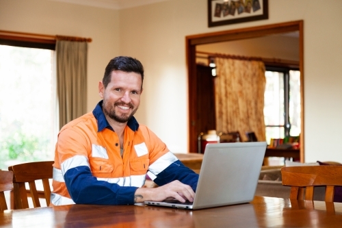 Happy man in his thirties working from home on laptop - Australian Stock Image