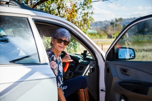 Happy mature aged woman getting into her car - Australian Stock Image