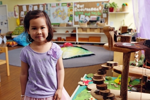 Happy multicultural child with wooden blocks puzzles in kindergarten - Australian Stock Image