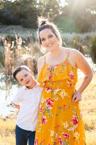 Happy parent standing with her son outside near dam - Australian Stock Image