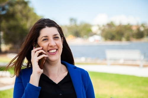 Happy person talking on her phone on a windy day outside - Australian Stock Image