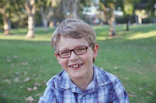 Happy preteen boy wearing glasses in the park - Australian Stock Image