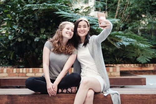 Happy students girl friends using mobile - Australian Stock Image