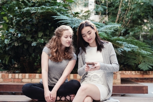 Happy students girl friends using mobile - Australian Stock Image