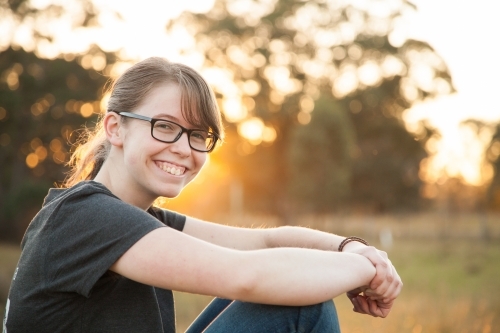 Happy teen girl sitting outside in the paddock - Australian Stock Image