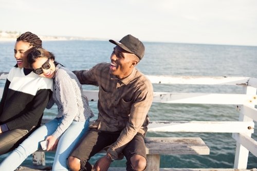 Happy teenage friends relaxing on a jetty - Australian Stock Image