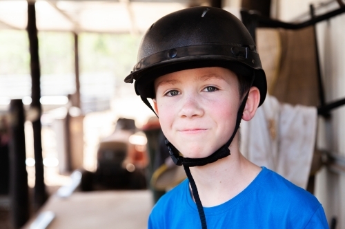 Happy tween boy wearing horse riding helmet - Australian Stock Image