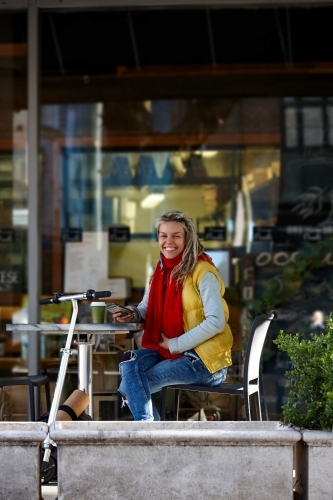 Happy woman with dreadlocks at cafe with electric scooter - Australian Stock Image